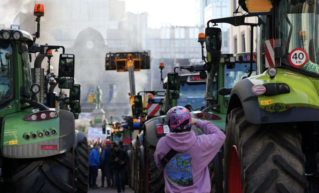 Farmers protest in a city street with tractors and people gathered