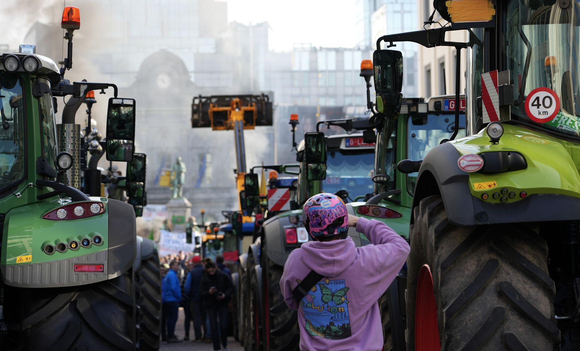 Farmers protest in a city street with tractors and people gathered