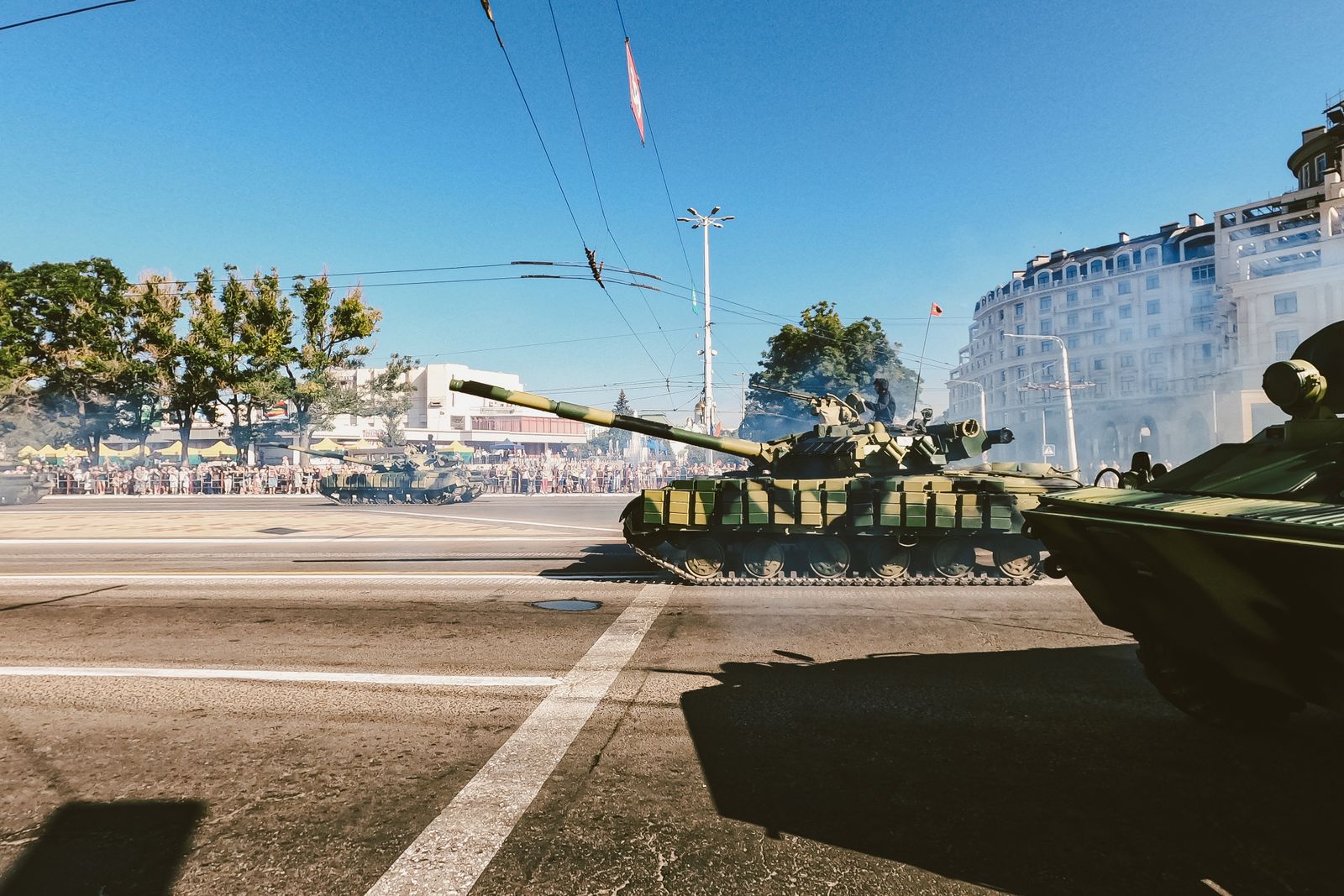 Military tanks moving through a street lined with spectators