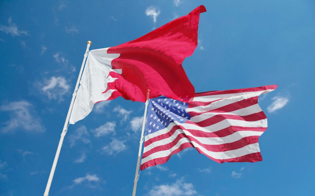 Flags of Bahrain and the United States waving against a bright blue sky