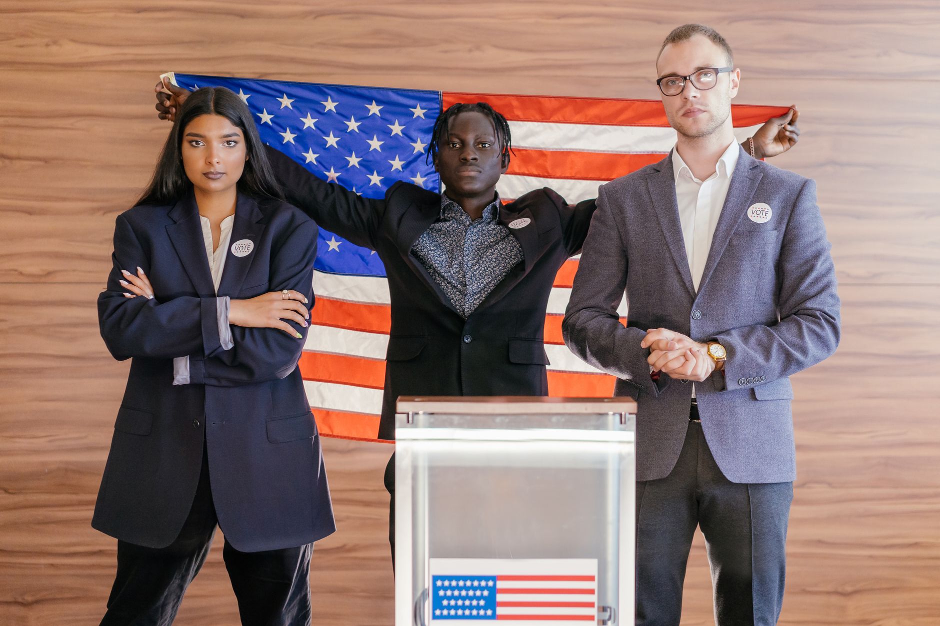 A group of diverse individuals standing in front of an American flag