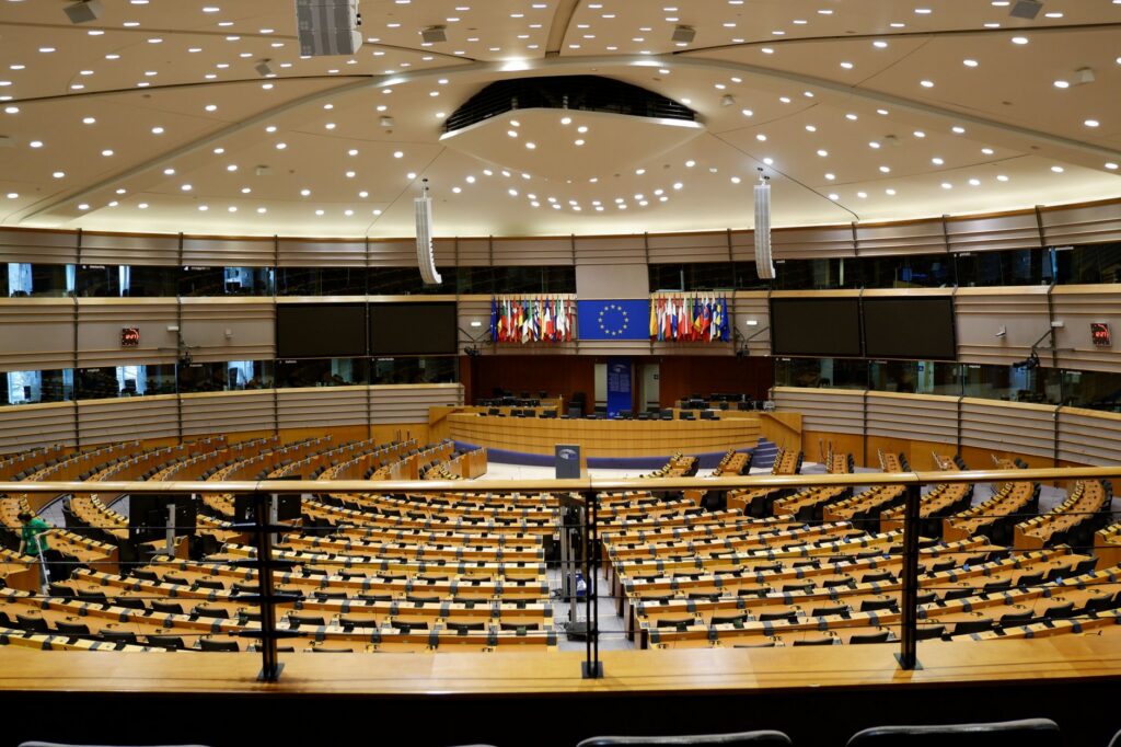 Empty European Parliament auditorium with rows of seats, representing institutional governance and organizational culture