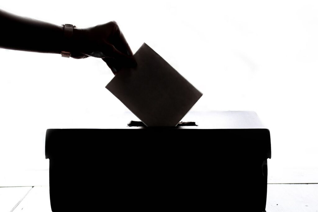 A hand placing a vote into a ballot box