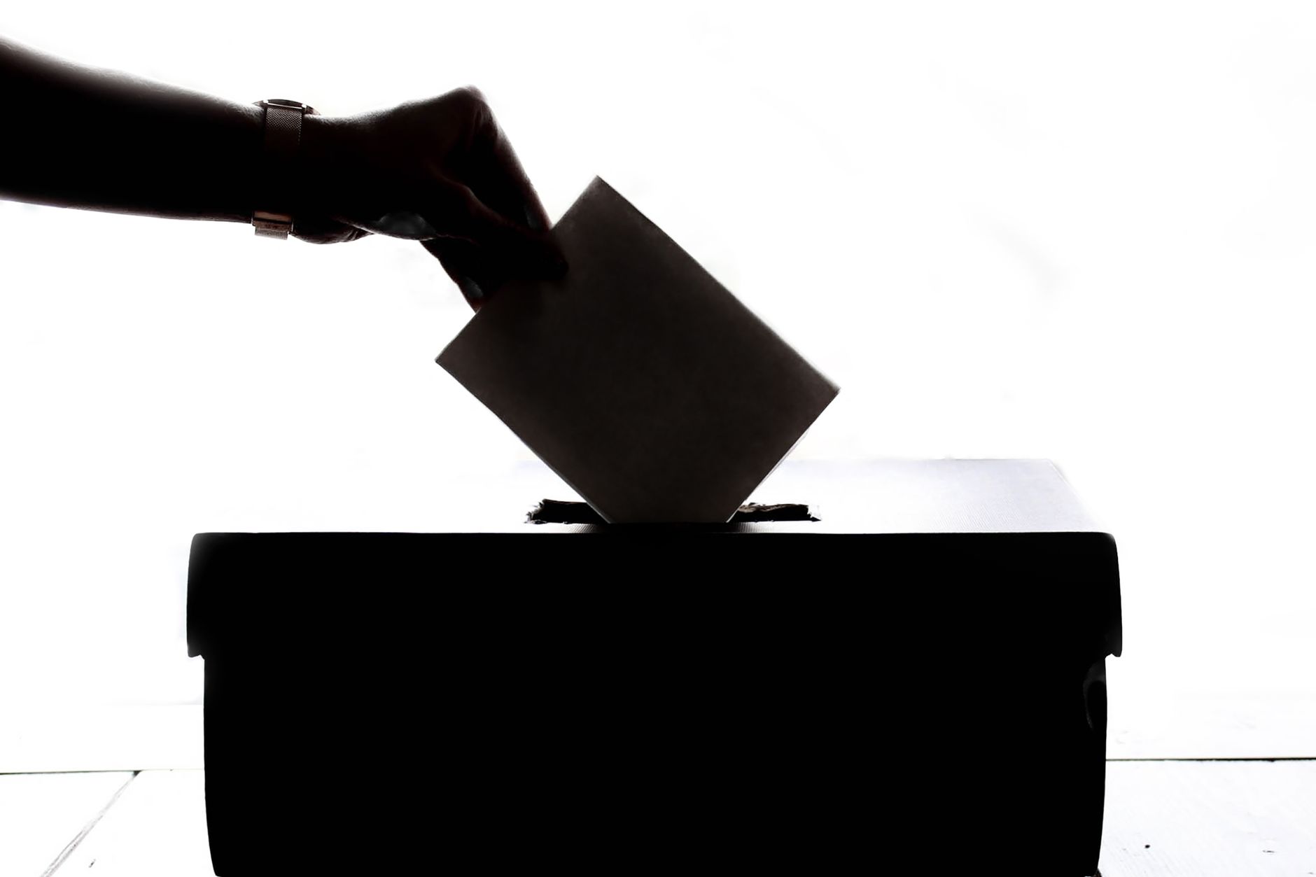 A hand placing a vote into a ballot box