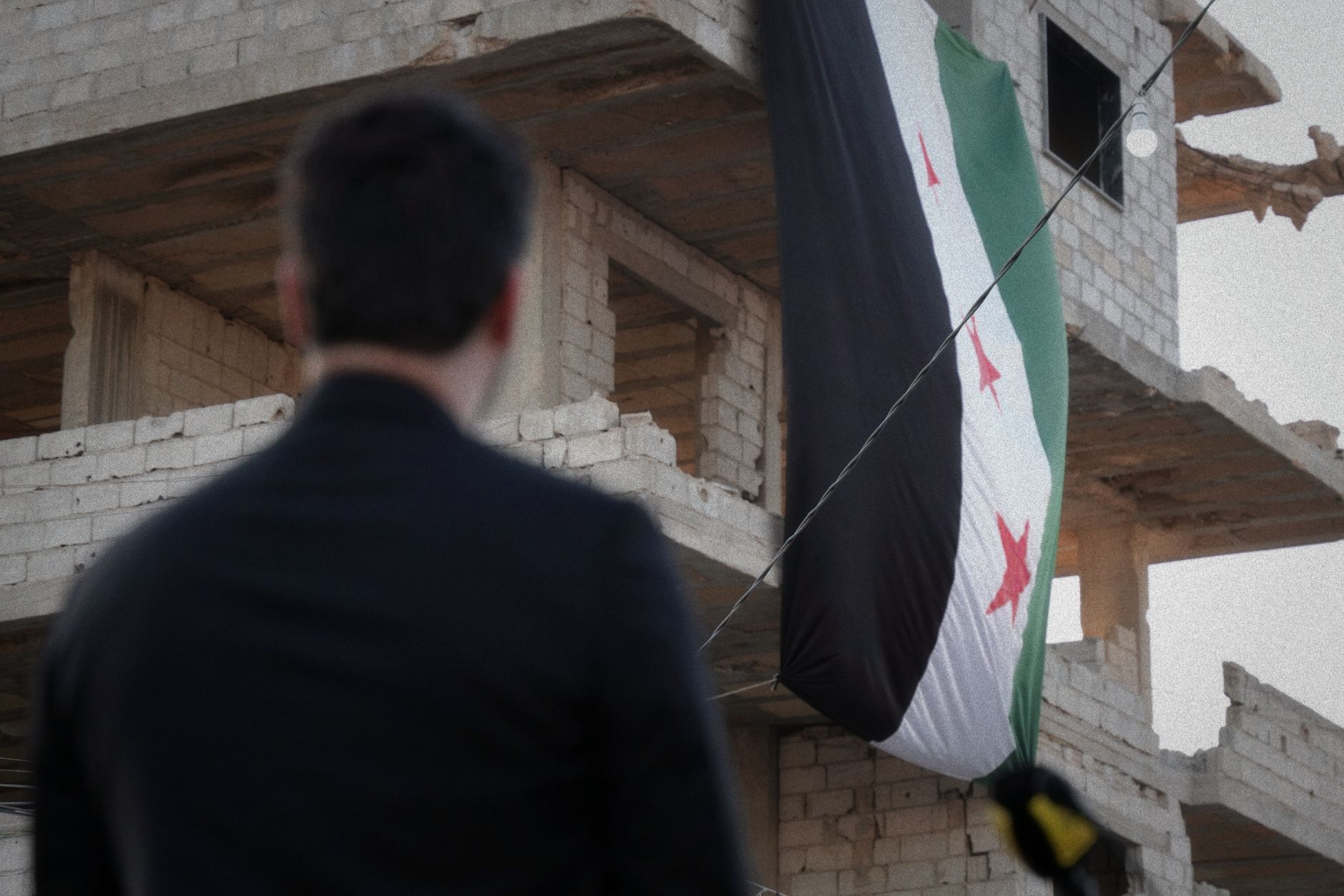 A Syrian flag draped over a war-torn building in Damascus