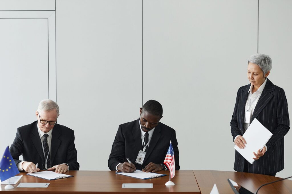 Officials signing an international agreement at a negotiating table