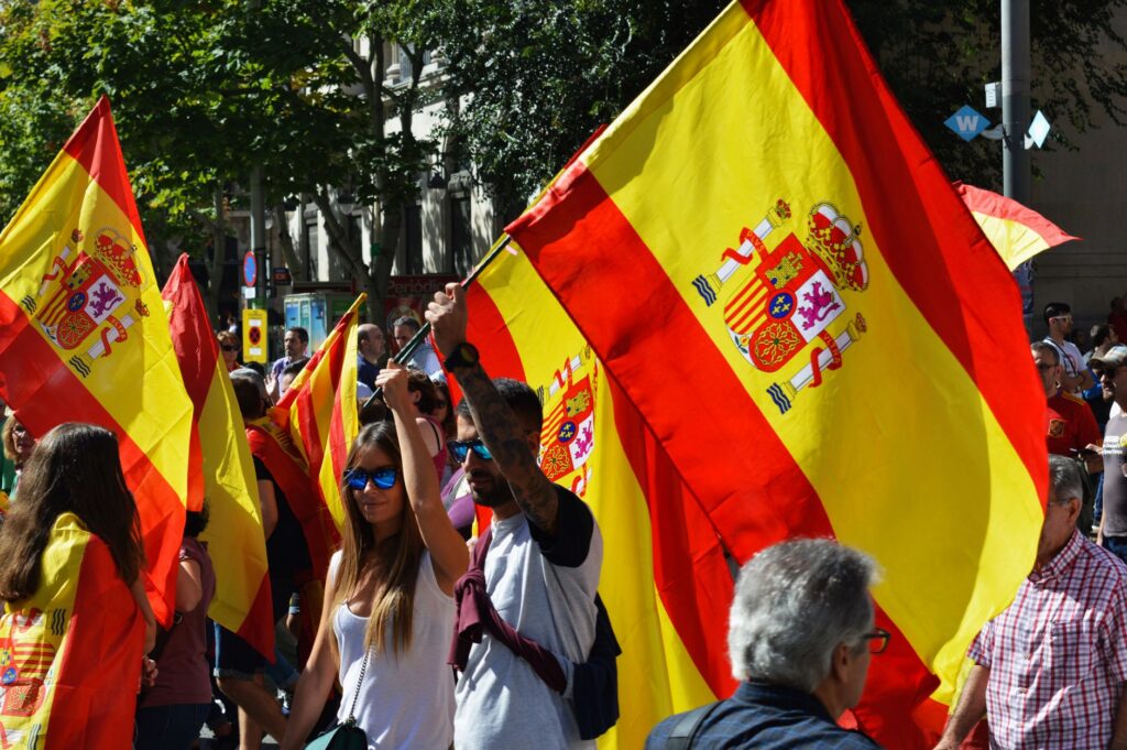 A street rally in Spain with people waving Spanish flags