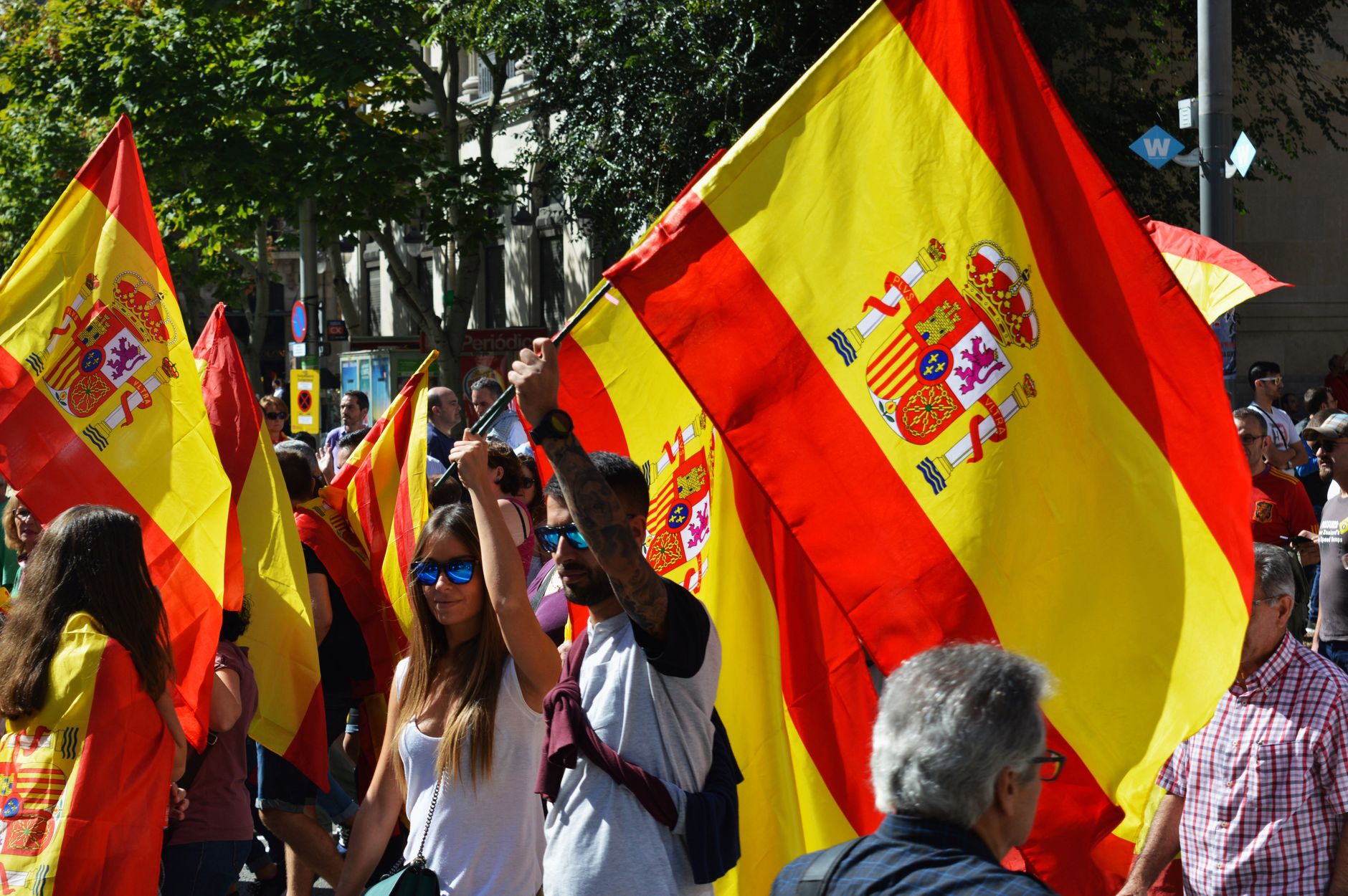 A street rally in Spain with people waving Spanish flags